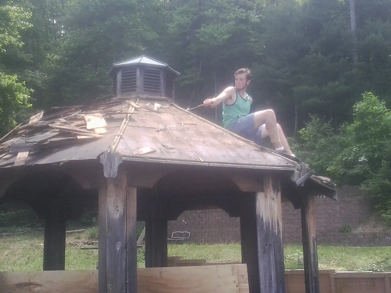 Tearing the old roof off a wooden gazebo before new shakes in Clare
