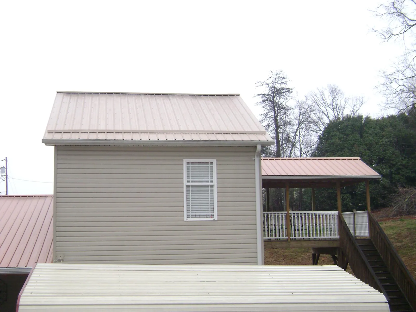 Tan metal roofs on a two story addition and attached porch, from a Roof Replacement job in Clare